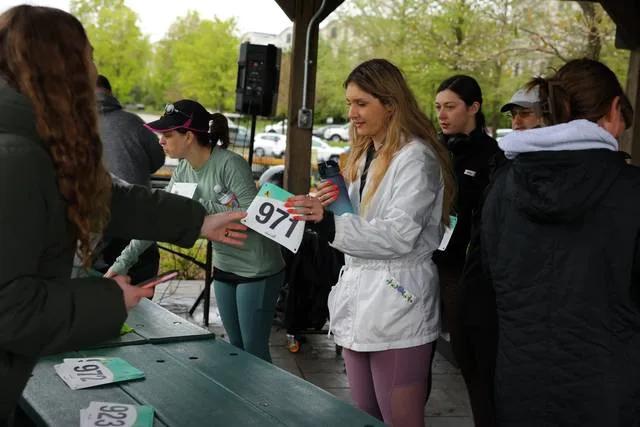 A volunteer handing a bib across the packet pickup table